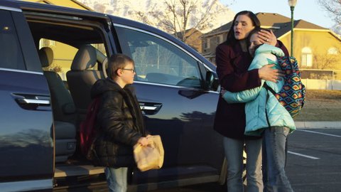 2 Kids get out of minivan and hug mother before running off to school