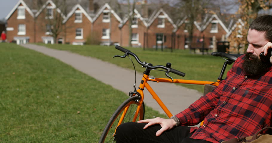 4k, A happy and cheerful cyclist using his cellphone while taking a break from cycling.