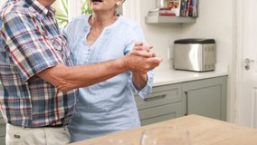 Old couple dancing in the kitchen with two cup of wine 