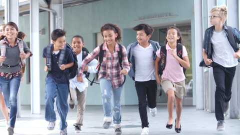 Group of 5th grade school kids running in a school corridor