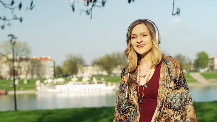 Girl listening music next to the river and enjoying it
