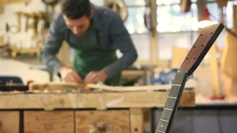 People and art, artisan work with mid adult man employed as craftsman in italian workshop with musical instruments, smoothing guitar body