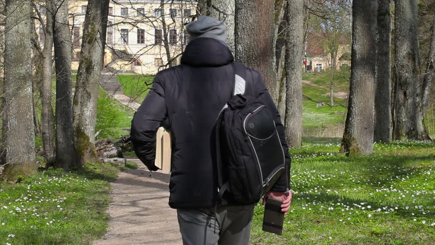 Man with two books walking away and take pictures on smart phone