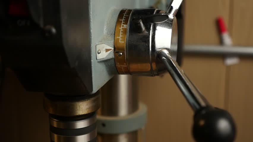 A man in a workshop using a drill press