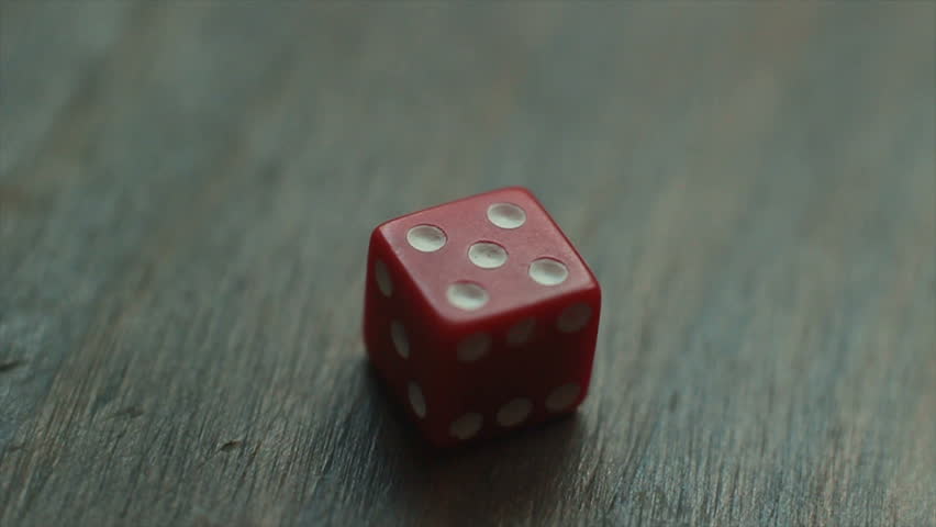 Red plastic die rolls on a wooden table, rolling all possible outcomes: one, two, three, four, five and six. Looped and easy to cut or extend.