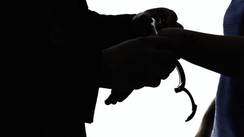A woman freed from handcuffs from a male officer. Silhouette detail shot of the hands.
