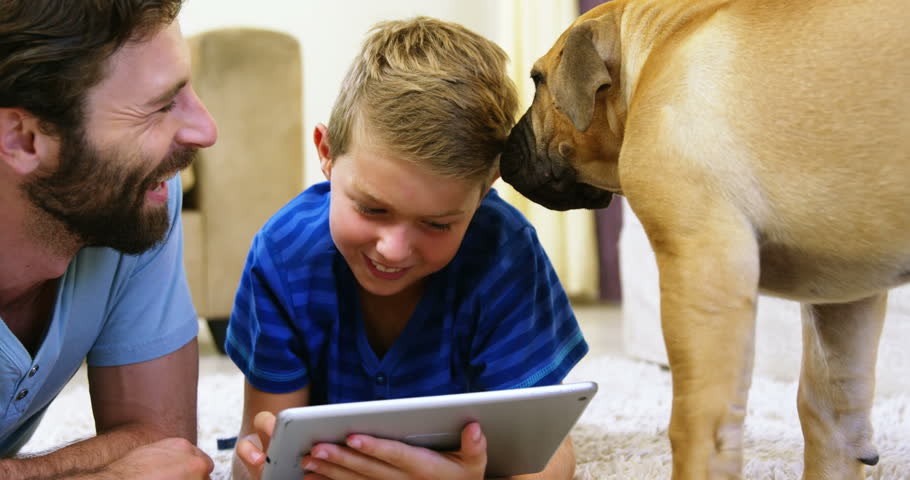 Father and son playing with a dog while using digital tablet Social distancing and self isolation in quarantine lockdown for Coronavirus Covid19