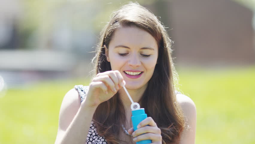 4K Young woman blows bubbles towards the camera, in slow motion