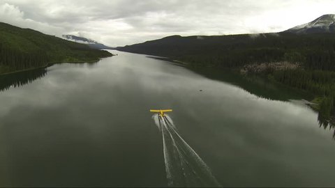 AERIAL CHASE SHOT OF FLOAT PLANE TAKE OFF IN LAKE BC CANADA