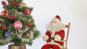 toy Santa Claus sits in a rocking chair and the other toy Santa Claus dances in eve of Christmas
