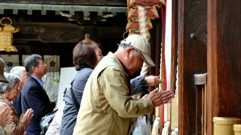 KYOTO, JAPAN -NOV 25, 2015: Tourists rang the bell for blessings at the Kitano Tenmangu Shrine in autumn, Kyoto, Japan. This shrine built in the northwest section of Kyoto over 1000 years ago