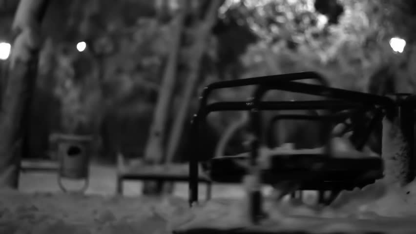 Night Winter Sad empty merry go round spinning in a playground black and white footage