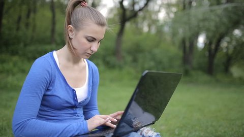the girl in front of laptop on the green grass