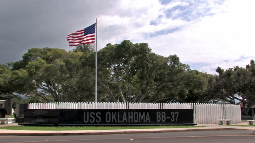 USS Oklahoma Memorial on Ford Island in Pearl Harbor, Honolulu, Oahu, Hawaii. Names of those killed in action aboard the battleship. Engraved sign with vertical posts with each name. US flag flying.