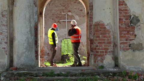 Building inspector talking on smart phone at old church before restoration