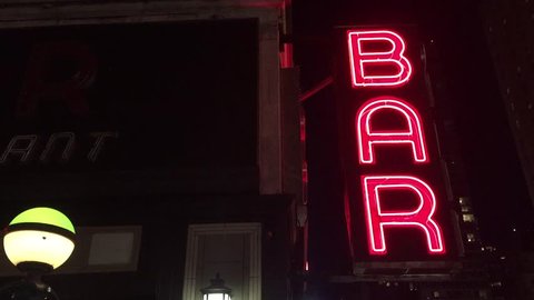 New York City Nighttime NX Establishing Shot CV of Bar Pub. Night exterior video footage of vintage neon sign. New York people go out at night to have fun, drink alcohol, go out on date, get together