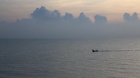 Fishing boat sailing across the sea at sunrise