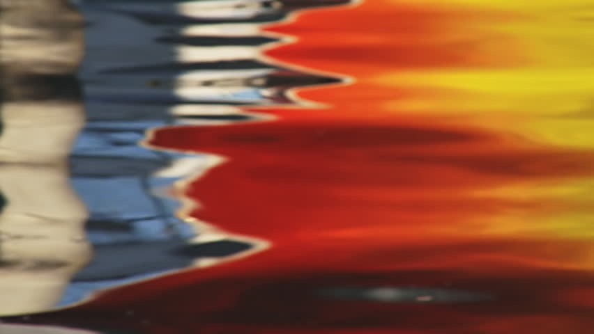 Rainbow-hued water as result of a reflection of a colorful boat's hull.  