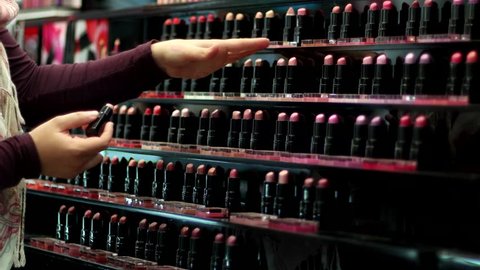 girl chooses shade of lipstick on the hand at cosmetics store  