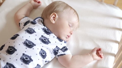 Peaceful adorable baby sleeping on his bed in a room. Soft focus. Sleeping baby concept. One year-old babyboy sleeps at home