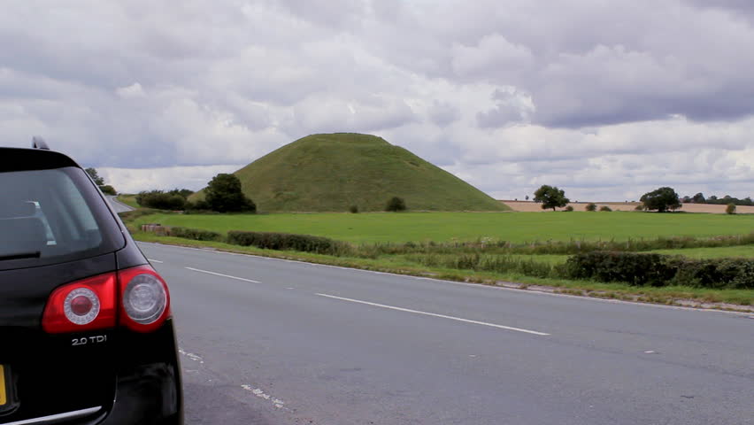 Silbury Hill with car moving in front of it.