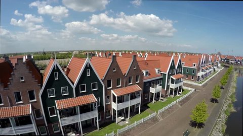 Aerial flying near the typical Dutch houses of Volendam then gaining height showing the harbor town is popular tourist attraction in Netherlands known for old fishing boats and traditional clothing 4k