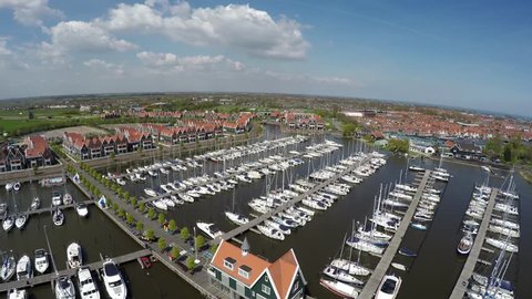 Aerial flying over  the recreational harbor of Volendam showing recreational boats ships harbor town is popular tourist attraction in Netherlands known for old fishing boats traditional clothing 4k