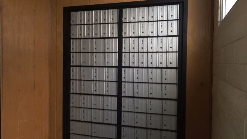 FOUNTAIN GREEN, UTAH - APRIL 2016: Older senior citizen man in yellow sweater, coveralls and fisherman hat with grey goatee getting mail from rural America Post Office Box.