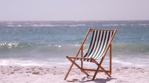 A deck chair is in the sand on the beach