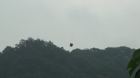 A chinese lantern descending on cloudy sky to reach vegetation. It is believed that with the release of flyers lanterns brings good luck and prosperity.