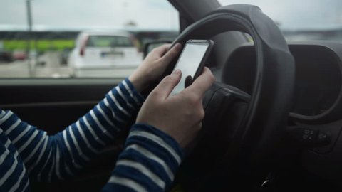 Woman using mobile smart phone while driving car, dangerous behavior in traffic