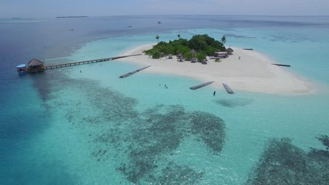 Aerial shot of a small tropical island in Maldives island, 2015.
Palms and jetty on the sandbank.