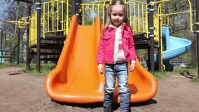 Little girl has fun riding on a slide at playground
