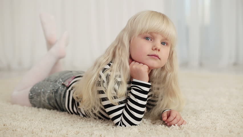 Happy little girl lying on the carpet 