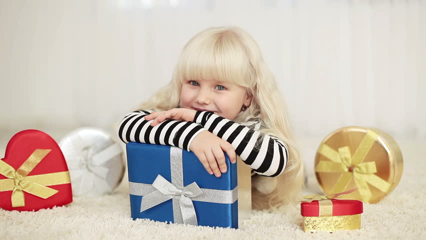 Happy little girl with gifts lying on the carpet 