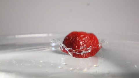 Fresh tasty red strawberry falling down into the transparent water with beautiful splash breaking the liquid surface on the white background isolated. Shot on high-speed camera in slow motion mode.