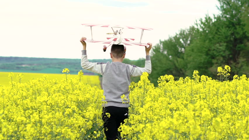 Happy kid running with toy airplane cross the rape. Camera behind boy Slowly