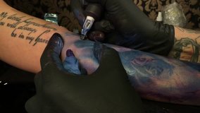 4K UHD video of professional tattoo artist makes a tattoo on a young girl's hand. 