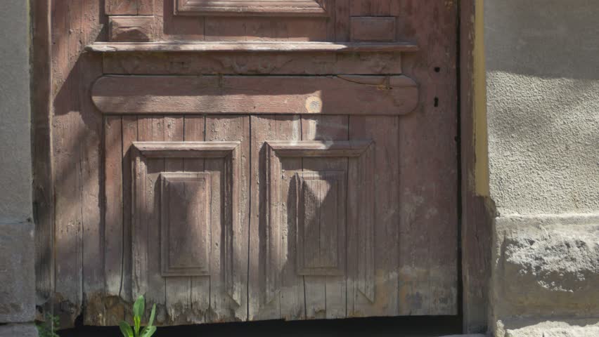 Tilt shot to a grunge wood abandoned house door with top windoes without glass.