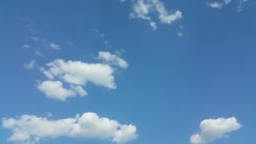 Time lapse clip of white fluffy clouds over blue sky.