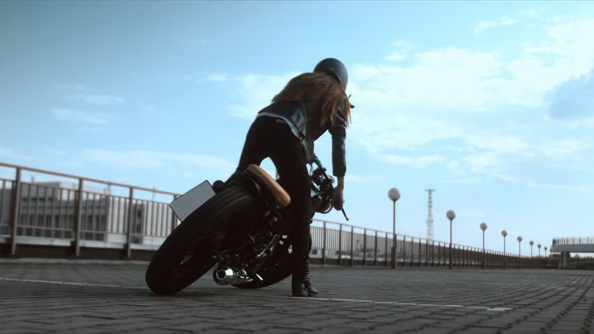Young sexy Caucasian female sits on a motorcycle, than falling on the ground, novice biker fail. 60 FPS slow motion. Blackmagic URSA Min