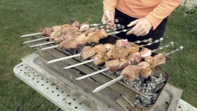 Girl cooks barbeque skewers with meat on hot coal ember brazier Outdoors picnic concept. 4K UHD video footage.