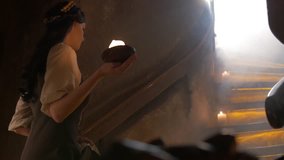 Medieval woman with a candle in his hand climbs the stairs in ancient castle interior in 4K UHD video.

