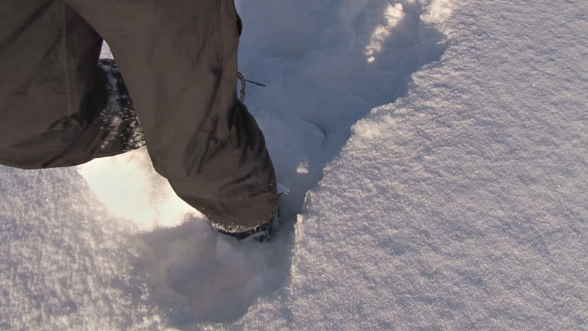 Self-shot of man walking through fresh snow in snow shoes.