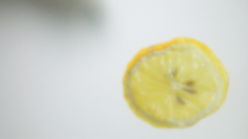 Round fresh lemon slice plunging into the transparent water  with explosive stunning splash, breaking the surface of liquid. Underwater high-speed slow motion shot on white background isolated. Camera Royalty-Free Stock Footage #16527382