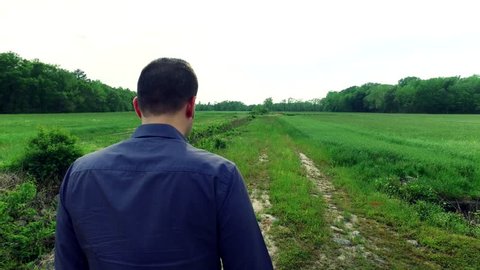 Panning View of a Man Taking a Pensive Journey through a Field 