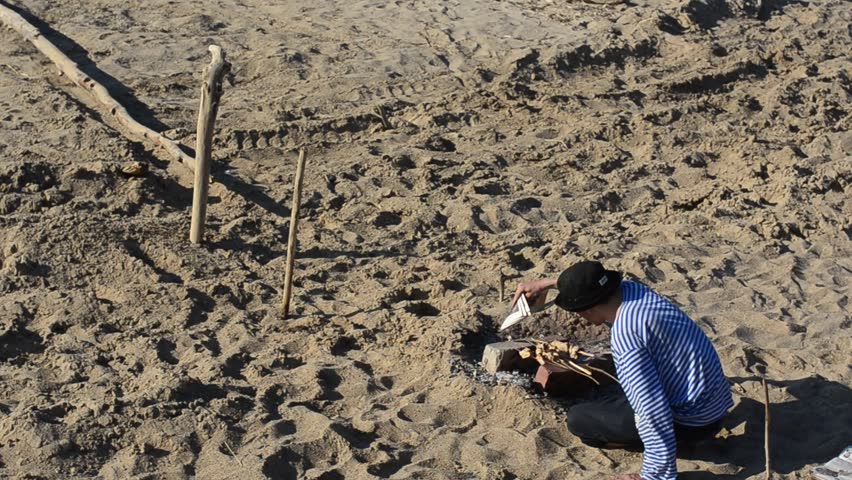 Man watching cooking meat on the beach.