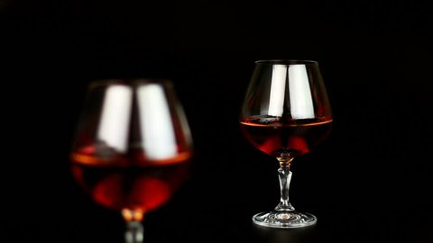 Man take a glass with brandy over black background