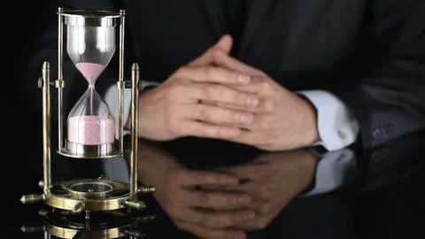 hourglass. time is running out. a man in a business suit