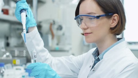 Portrait of Young Woman Scientist Working in Laboratory, using Micropipette. Shot on RED Cinema Camera in 4K (UHD).